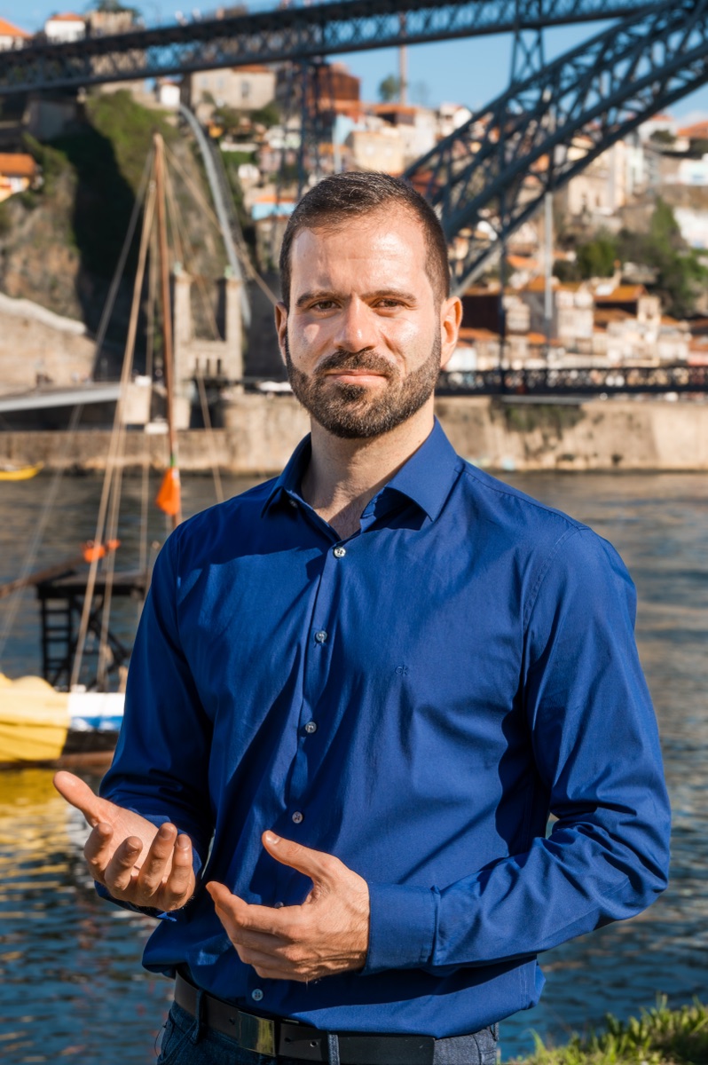André Freitas explaining something by the Douro river, with the Luís I bridge behind him